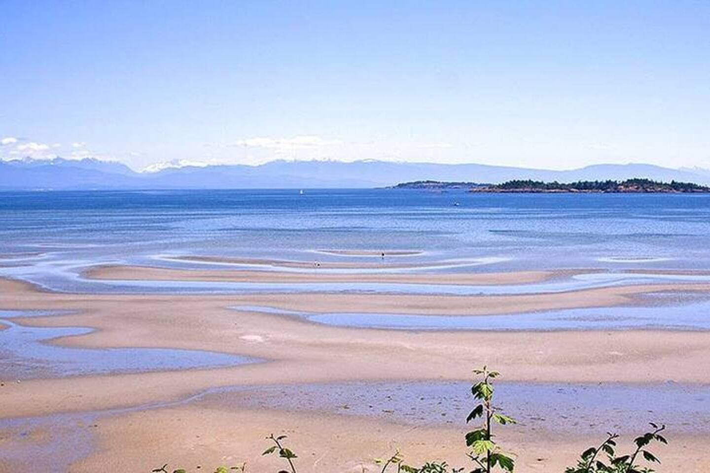 Ein Strand mit klarem Wasser und einer entfernten Insel.