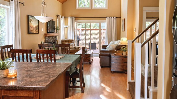 A spacious living area with a dining table, sofas, and a staircase.