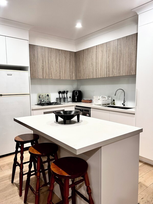 Una cocina moderna con una isla central, armarios de madera y lavavajillas integrado.