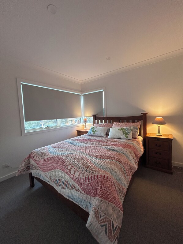A bedroom with a bed, bedside tables, and a window.