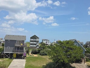 A coastal residential area with multiple two-story houses, a clear sky, and a grassy lawn. - Ocean & sound views, hot tub, in Nags Head. (Nags Head)