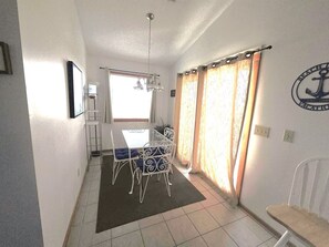A dining area with a table and chairs, a window with curtains, and a wall with a logo. - Ocean & sound views, hot tub, in Nags Head. (Nags Head)