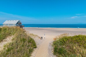 Ein Strandweg, der zu einem Haus mit Meerblick führt.