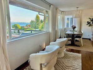 Ein Zimmer mit Blick auf ein Gewässer, einem Essbereich mit Tisch und Stühlen sowie einem weißen Sofa.