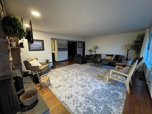 Ein Wohnzimmer mit Kamin, Sofas, Couchtisch und Fernseher.