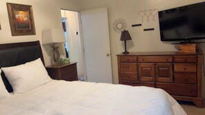 A bedroom with a bed, a dresser, a television, and a wall decoration.
