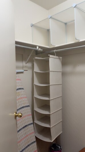 A storage closet with shelves and a hanging rack.