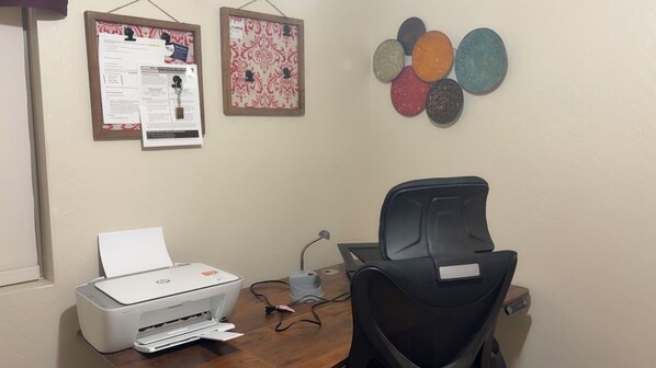A room with a printer, a chair, a desk, and two bulletin boards on the wall.