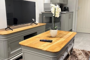 A kitchen area with a built-in TV, a coffee maker, and a potted orchid on the countertop. - Guesthouse Sleeps 2 with Parking (Bootle)