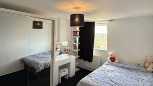 A bedroom with a bed, a desk, a mirror, a hanging lamp, and a teddy bear. - Apartment Sleeps 2 with Free Parking (Orpington)