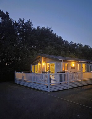 A single-story cabin with a porch, surrounded by trees.
