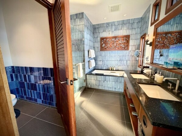 A bathroom with two sinks, a bathtub, and a shower area.