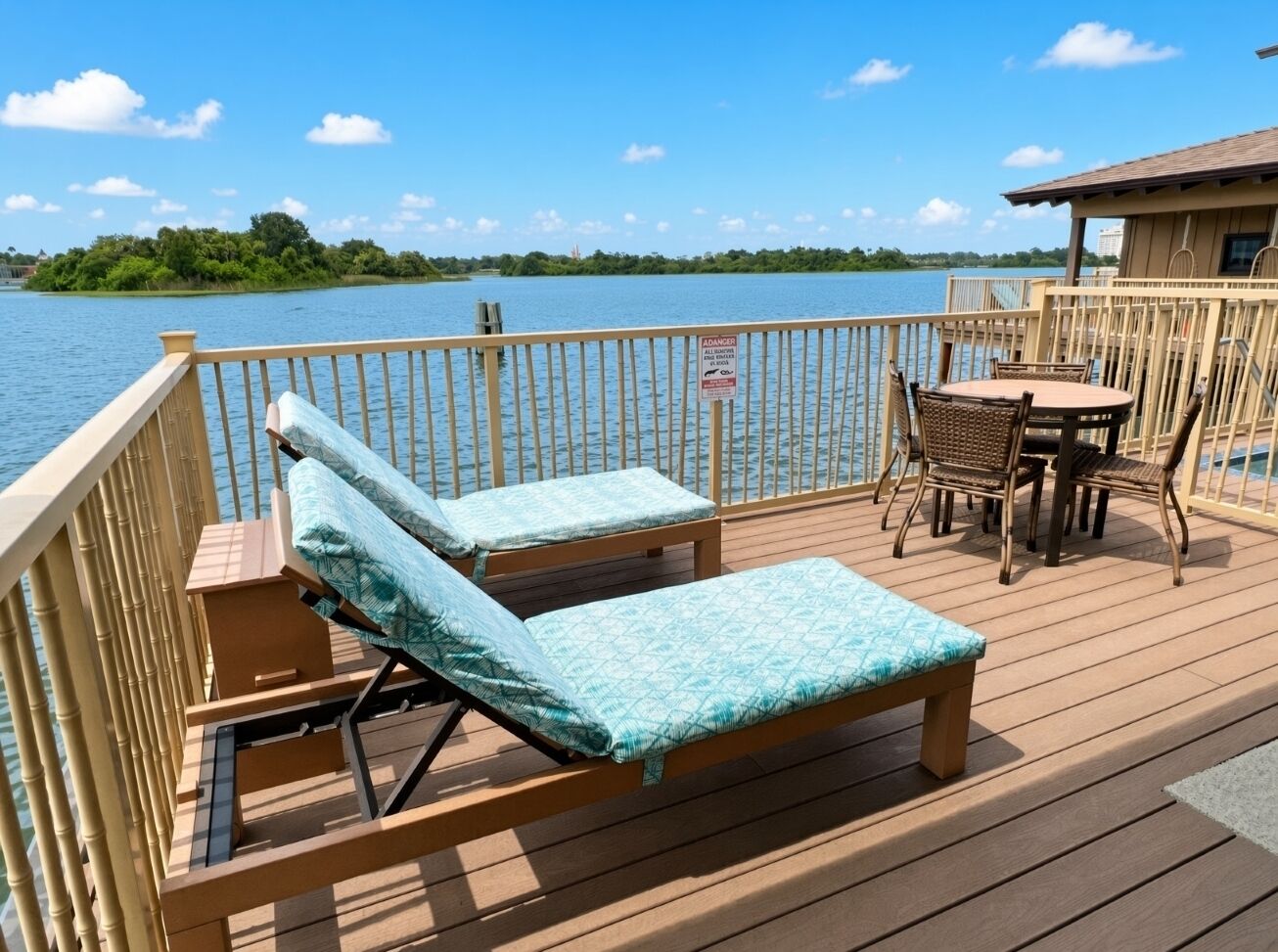 A wooden deck with lounge chairs and a table, overlooking a body of water.