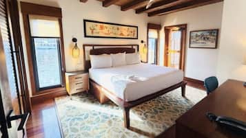 A bedroom with a large bed, wooden headboard, bedside tables, a desk, and a chair.