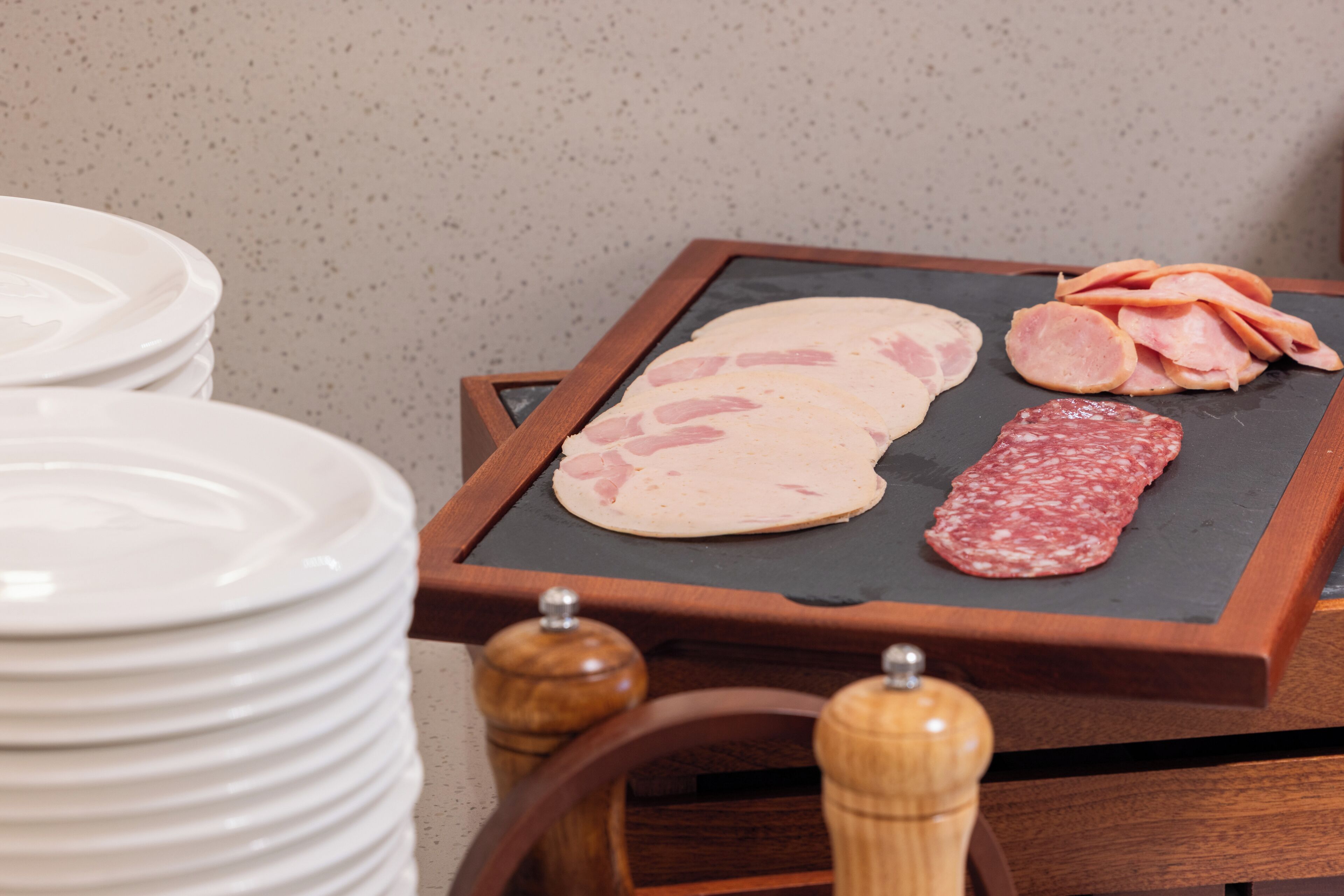 A wooden table with a black slate surface displaying various meats.