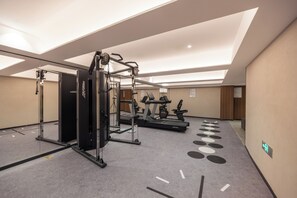Uma academia com equipamentos de ginástica, incluindo uma máquina de pesos e esteiras.
