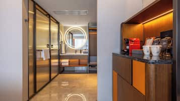 A modern hotel bathroom with a vanity, towel rack, and a mirror with a circular light.