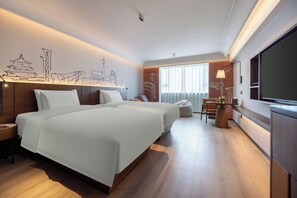 Quarto de hotel com uma cama grande, uma escrivaninha, uma cadeira, uma televisão e uma parede com um mural da paisagem urbana.