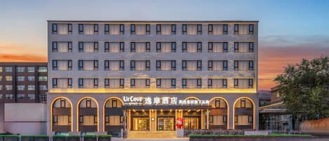 Un hotel de fachada moderna, con varios pisos y una entrada destacada con letreros iluminados.