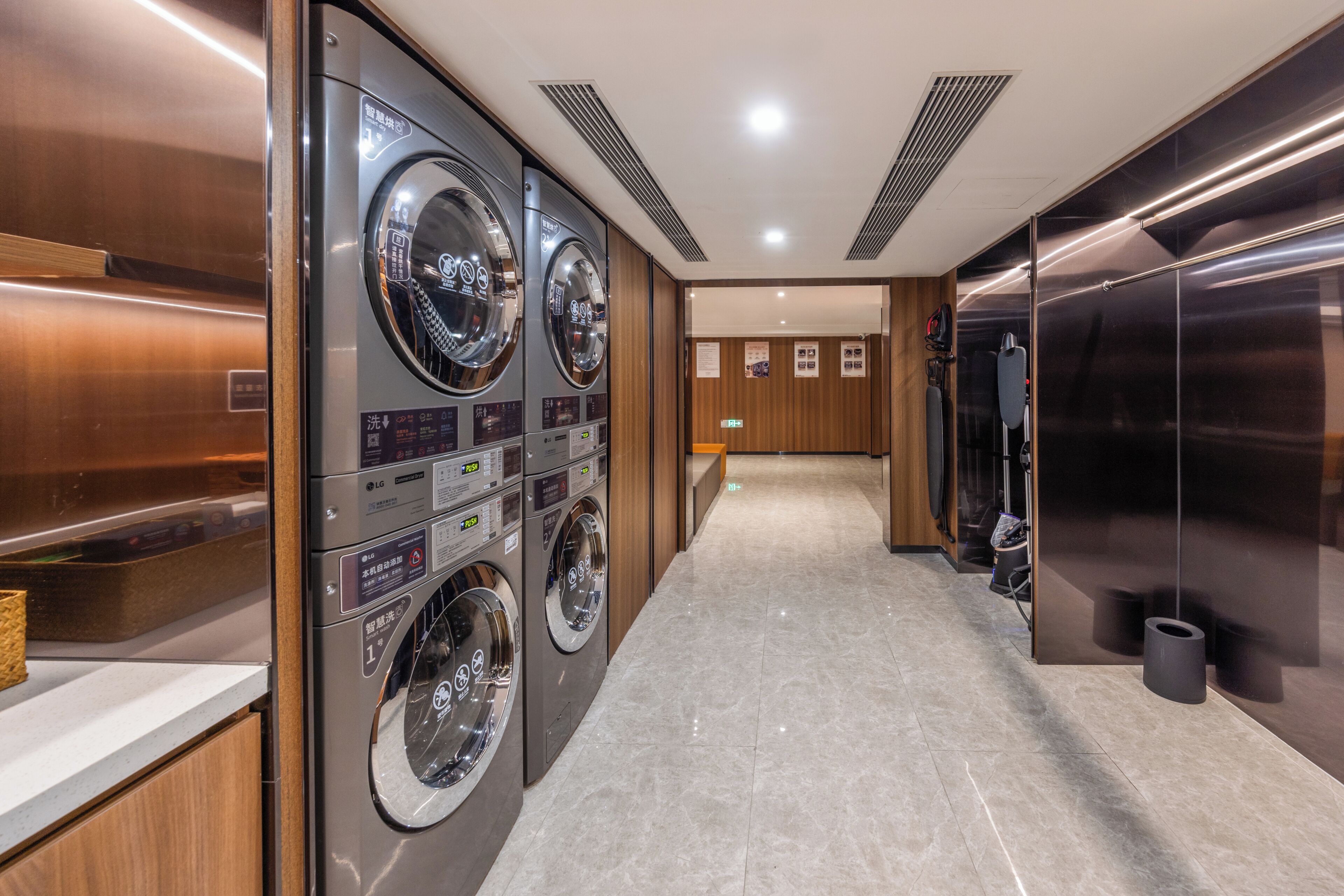 A hotel laundry room with multiple washing machines, a wooden reception desk, and a tiled floor.