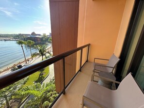 A balcony with a view of a beach and water, furnished with chairs and a table. - Orlando | Couples Tropical Getaway | Pool + Beach (Golden Oak)