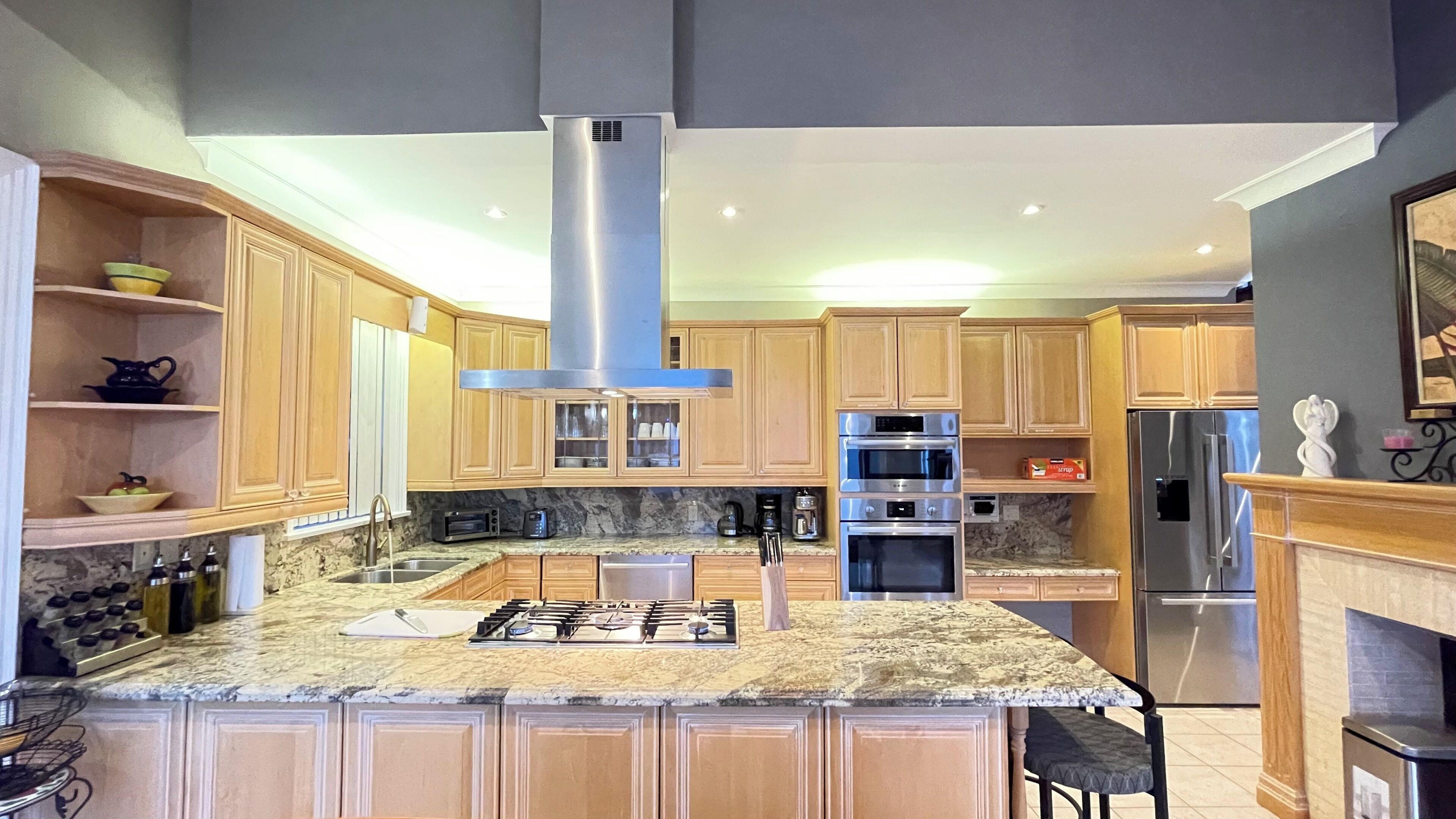 A modern kitchen with granite countertops, stainless steel appliances, and wooden cabinetry.