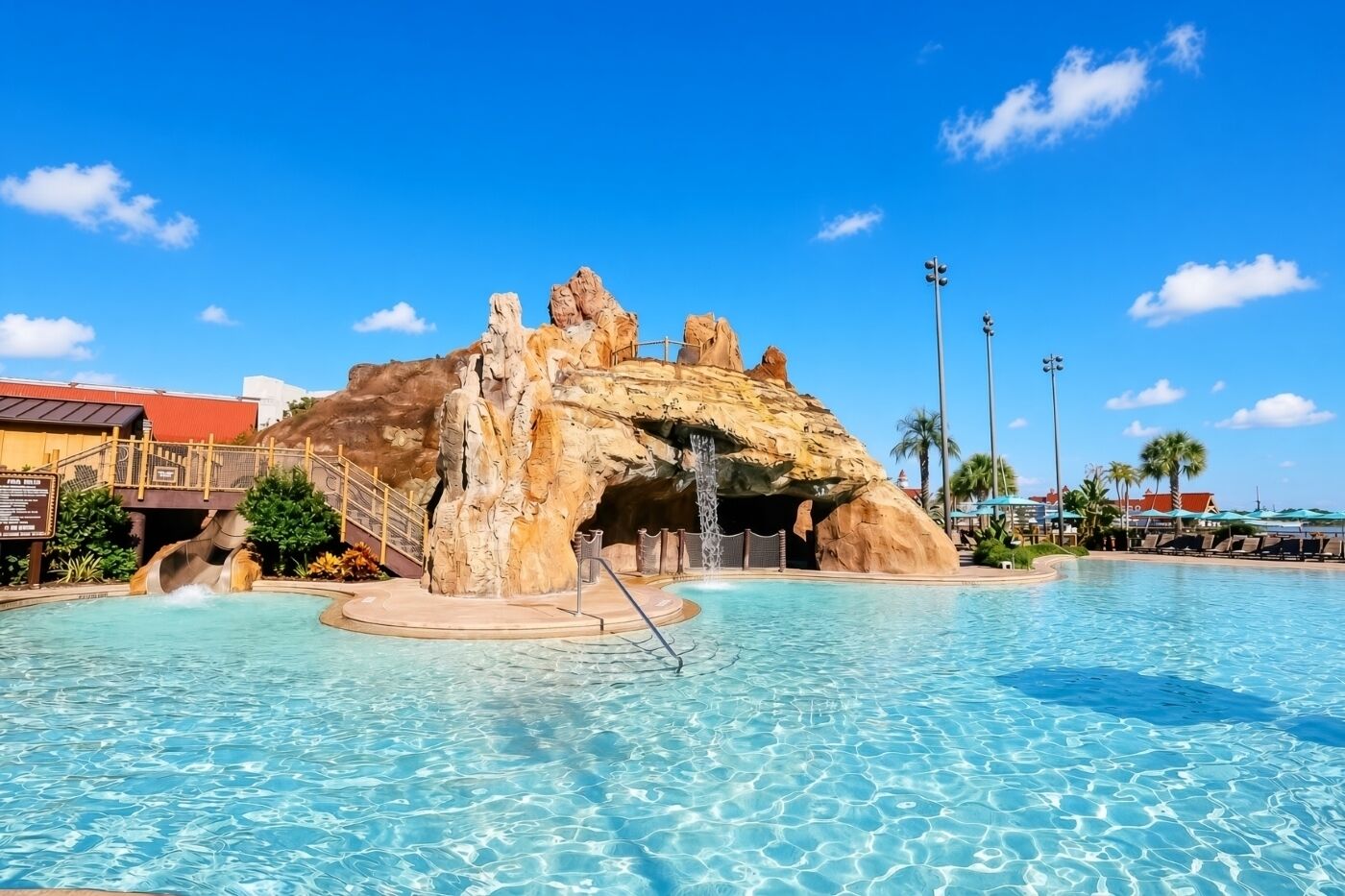 A swimming pool with a rock formation and a bridge.