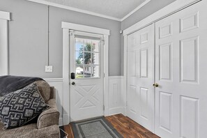 A hallway with a white door, a window, and a doorbell.