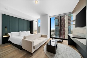 Ein modernes Schlafzimmer mit einem Bett, einem Sofa, einem Couchtisch und einem großen Fenster mit Blick auf die Stadt.