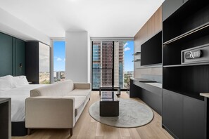 A modern hotel room with a bed, a sofa, a coffee table, and a large window offering a city view. - Elegant E11EVEN Residence with ELITE Amenities (Miami)