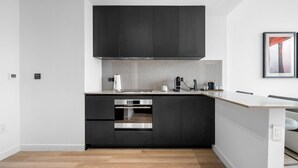 A modern kitchen with dark cabinetry, a stainless steel oven, and a minimalist design. - Luxury E11EVEN | Skyline Views & Resort Amenities (Miami)