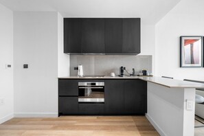 Una cocina moderna con armarios oscuros, horno de acero inoxidable y diseño minimalista.