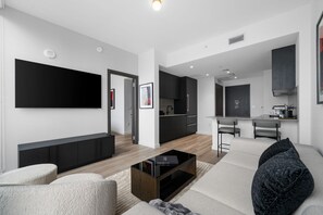 Una sala de estar moderna con un televisor de pantalla plana, una mesa de centro y asientos.