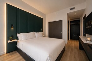A modern hotel room with a large bed, a bedside table with a plant, a dark wardrobe, and a flat-screen TV on the wall. - 44th-Floor Condo w/ Stunning Miami Sunset View (Miami)