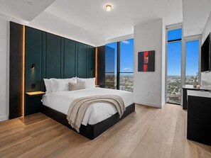Ein modernes Schlafzimmer mit einem großen Bett, einem Nachttisch und Blick auf die Stadt durch große Fenster.