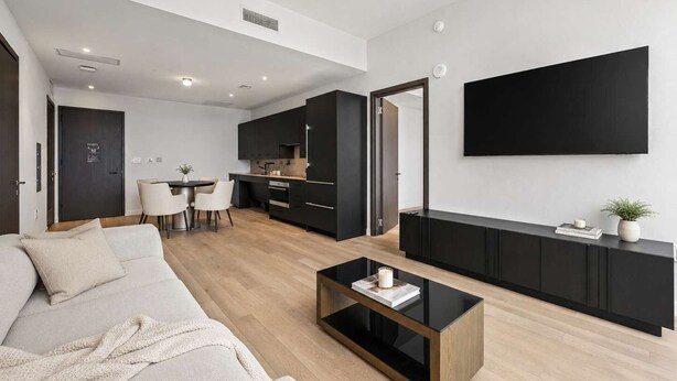 Een moderne woonkamer met een bank, een salontafel en een eetgedeelte met stoelen.