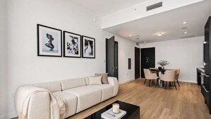 Een moderne woonkamer met een bank, een salontafel, en een eethoek met stoelen en een tafel.