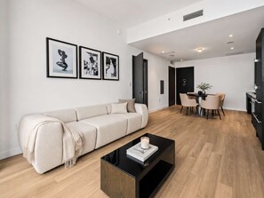 A modern living room with a sofa, a coffee table, and a dining area with chairs and a table. - 44th-Floor Condo w/ Stunning Miami Sunset View (Miami)