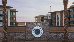 A modern building with a stone wall and a sign that reads 'REVOLVE AT BALLPARK VILLAGE.' - Landing | Modern 2BD, Game Room, Gym (Goodyear)