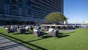 A rooftop terrace with outdoor seating and a view of a modern building. - Landing | Incredible 1BD, Courtyard (Orlando)