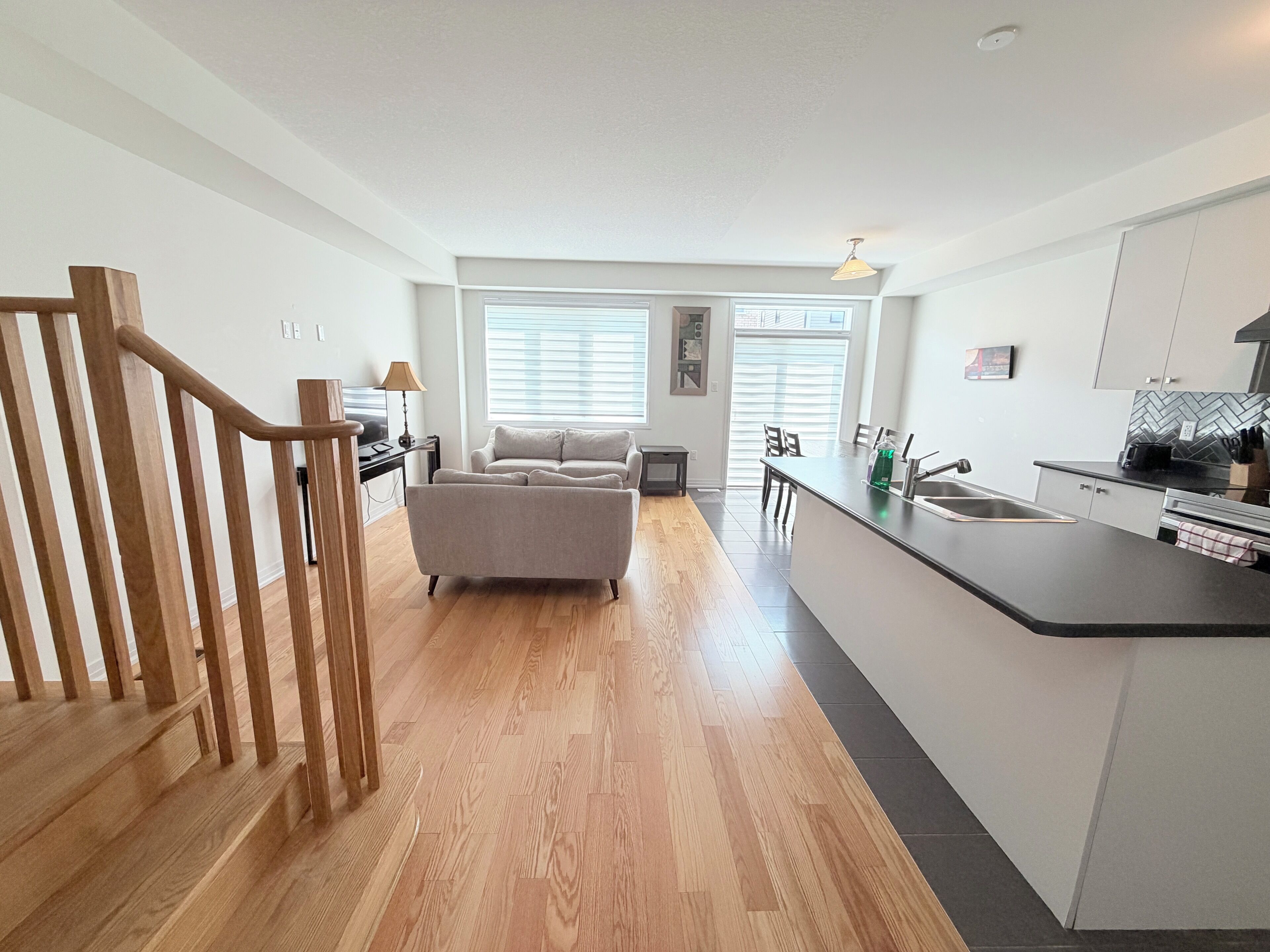 Una cocina moderna con una isla central, suelo de madera y una zona de comedor con sofá.