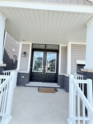 A two-door entrance with a white porch railing, a doormat, and a mailbox. - Family Home Near Niagara Falls | Thorold | Minutes drive to all attractions (Thorold)