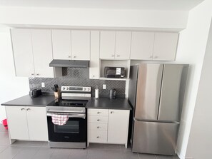 Eine moderne Küche mit Edelstahlgeräten, weißen Schränken und einer Küchenwand mit Fischgrätmusterfliesen.