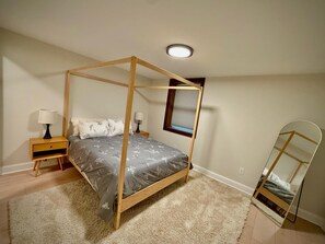 A bedroom with a four-poster bed, two bedside tables with lamps, a window with blinds, and a mirror on the wall. - The Pause, 4-bedroom Modern Timber Retreat in Berkeley Springs (Berkeley Springs)