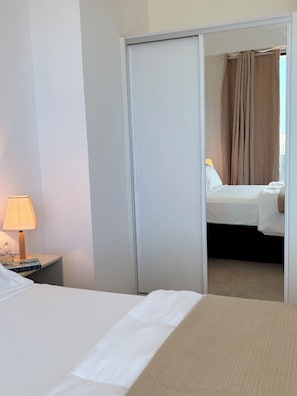 A hotel room with a bed, a nightstand with a lamp, and a mirror reflecting another room with a bed and curtains. - Joli Penthouse 60m² Rooftop Terrace, 360° View (Sal)