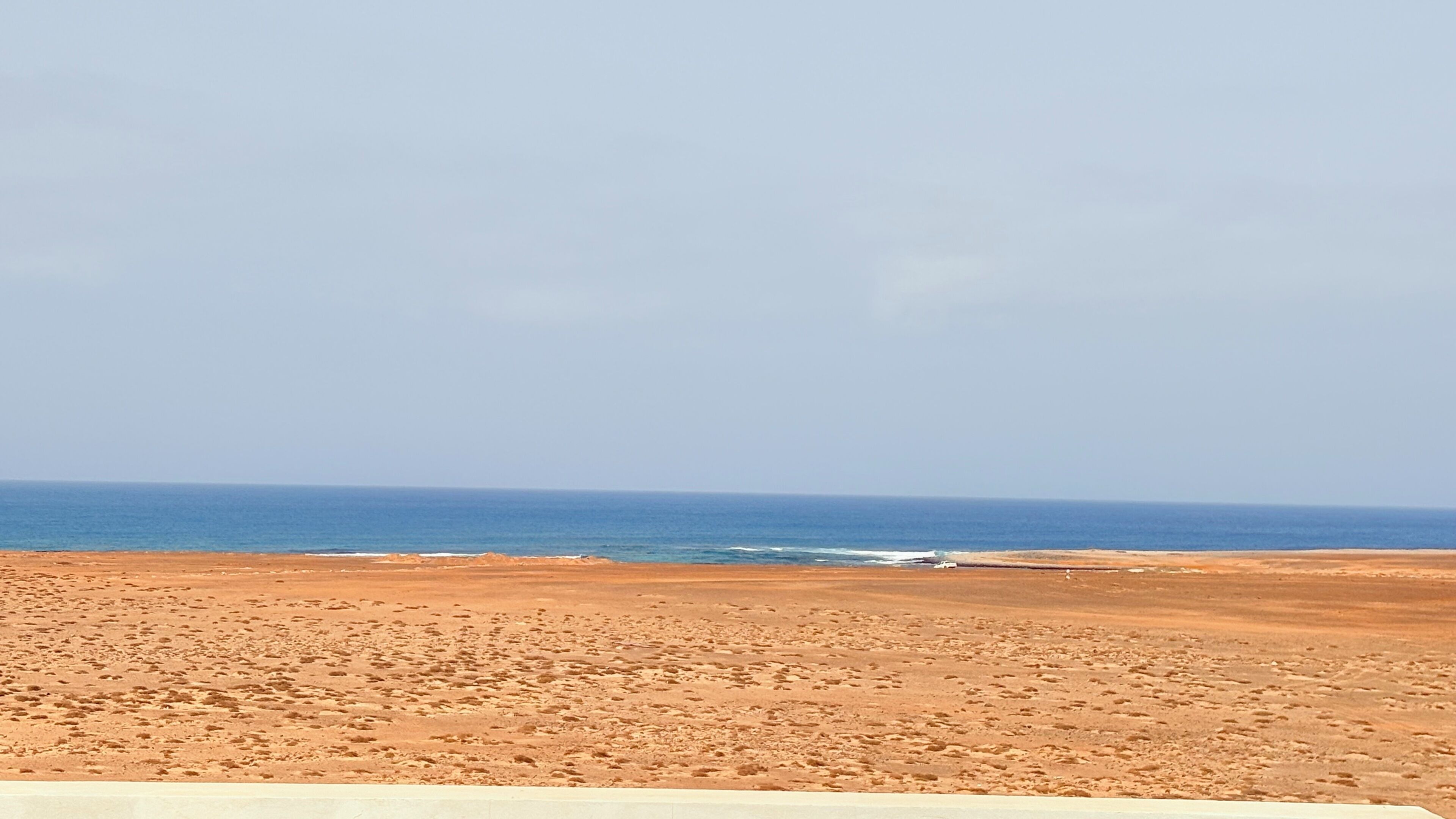 A beach with a clear view of the ocean and a sandy landscape.