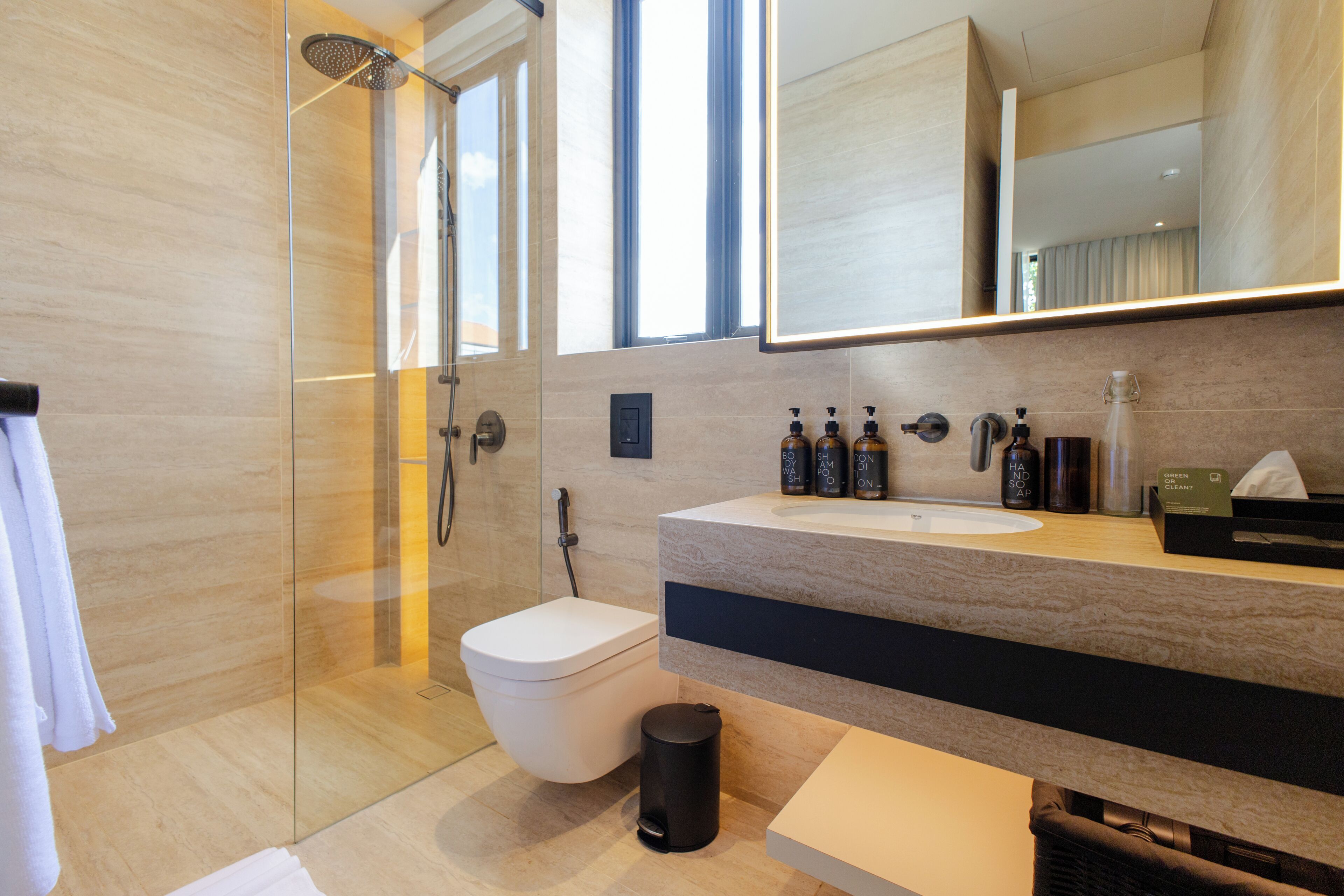 Un baño moderno con ducha de vidrio, inodoro blanco y tocador con espejo.