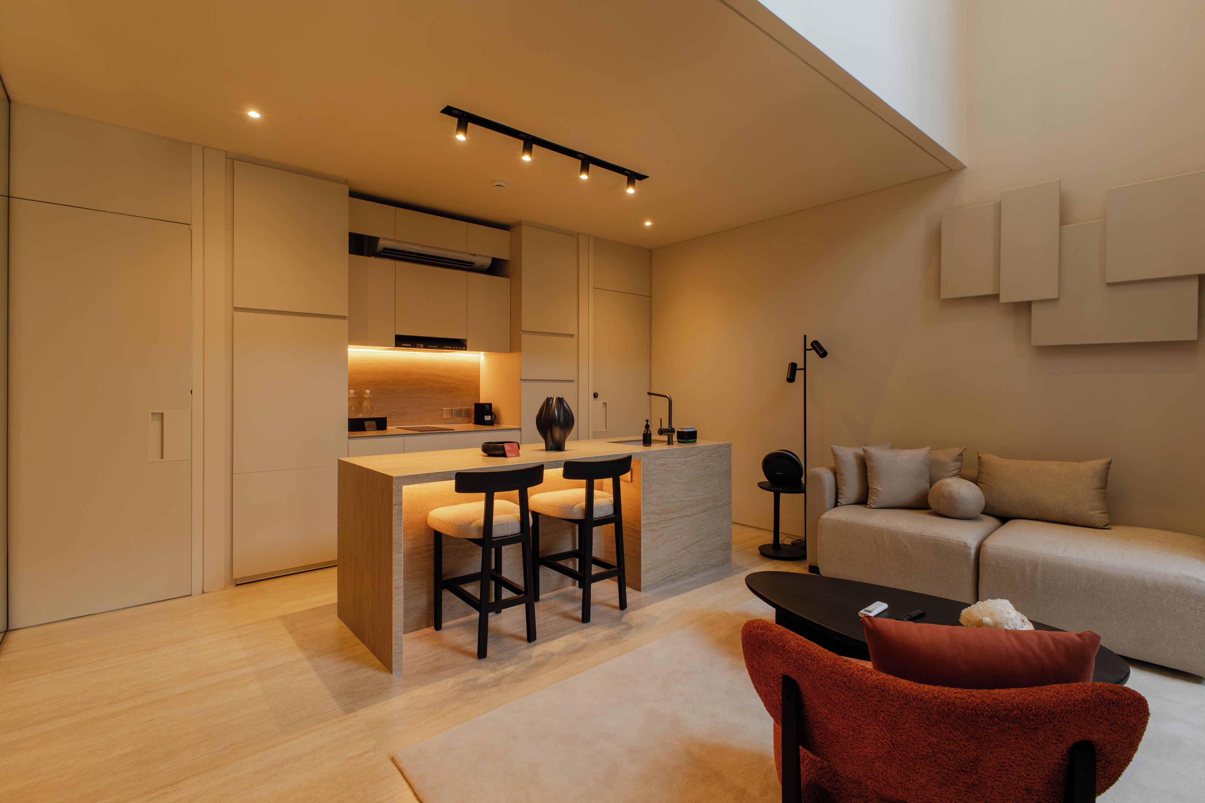 Una cocina moderna con una isla central, taburetes de bar y una mesa de comedor.
