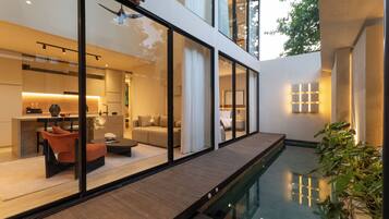A modern house with a glass-enclosed patio, a pool, and a wooden deck.