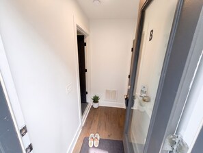 A hallway with a door, a potted plant, a mat, and a shoe rack. - Private 1BR King Suite • Near Downtown Nashville (Nashville)